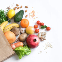 Organic vegan food Healthy food background. Healthy vegan vegetarian food in paper bag vegetables and fruits on white, copy space. Shopping food supermarket and clean vegan eating concept. (Healthy food background. Healthy vegan vegetarian food in paper bag vegetables a